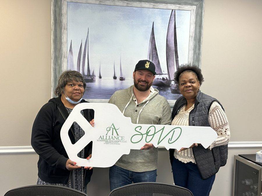 Three clients holding the oversized SOLD key at closing