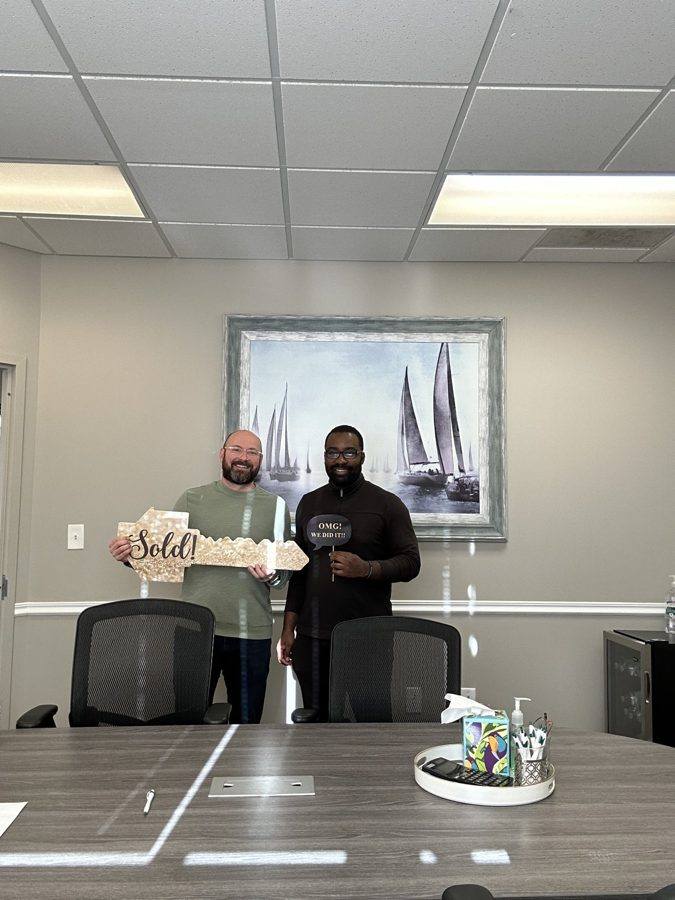 Two clients holding a Sold! key at the title office