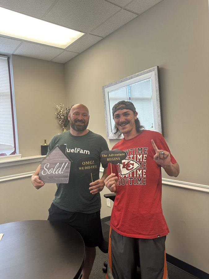 Two people celebrating a closing with Sold! props
