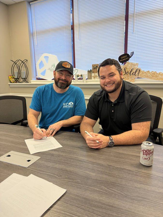 Two people signing paperwork at the closing table