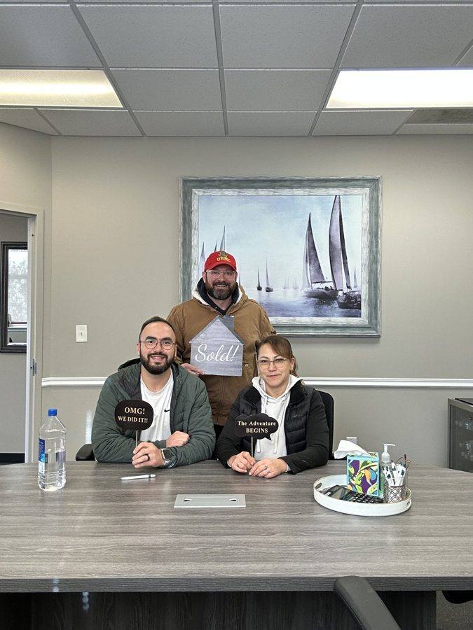 A family at their closing with a Sold! sign