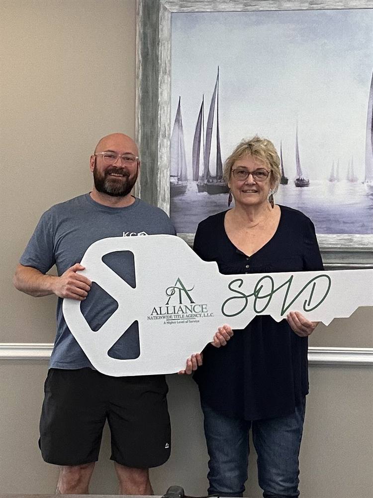 Two clients holding an oversized SOLD key at their closing